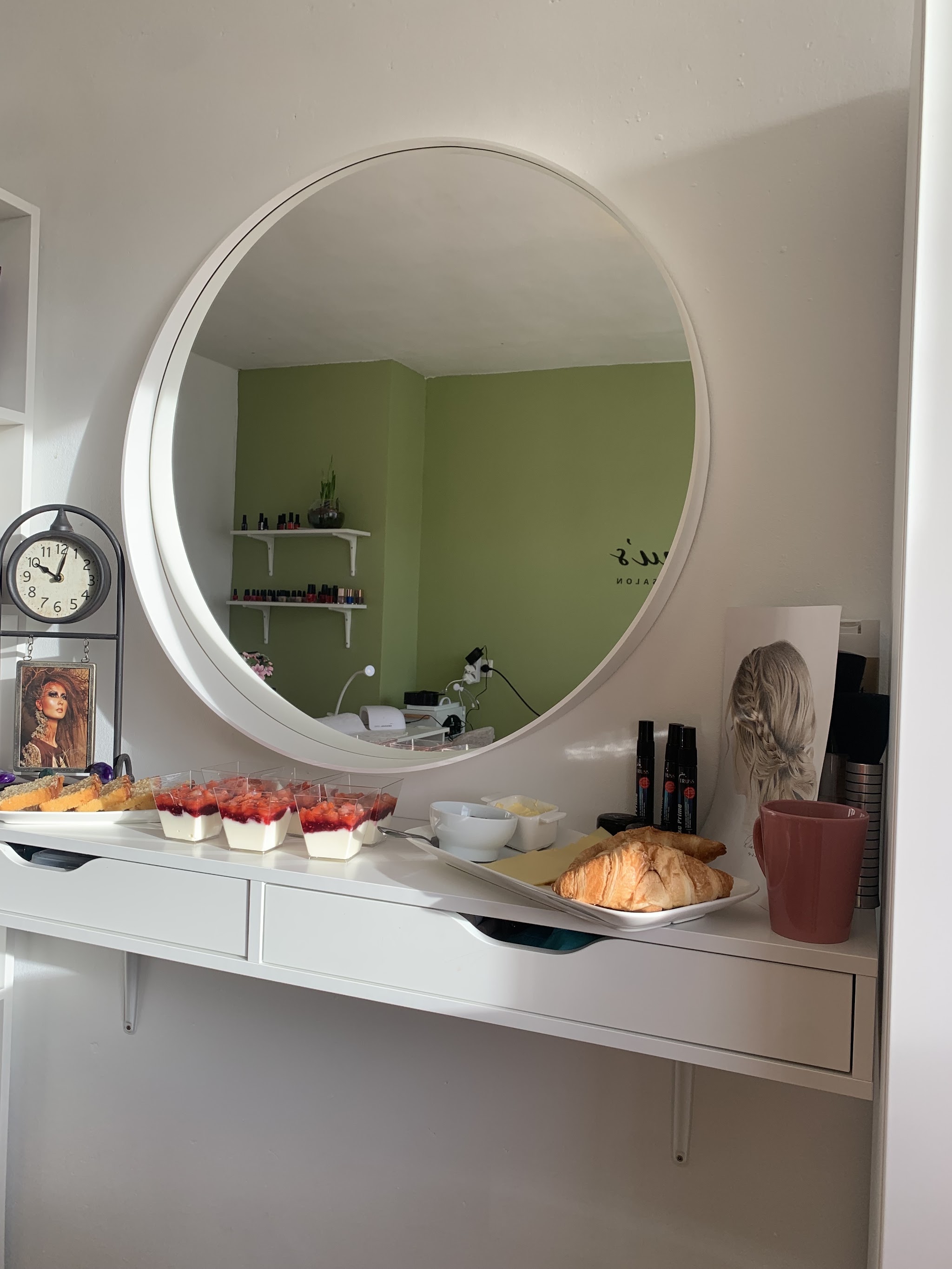 De ronde spiegel en het witte kastje in de salon, met croissants, gebak en een kop koffie