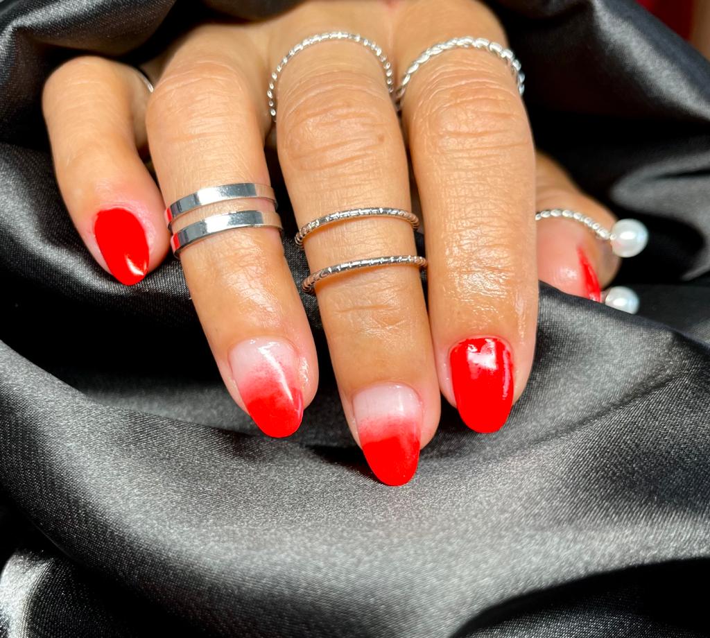 Rode ombre BIAB-nagels met zilveren ringen op zwart satijn