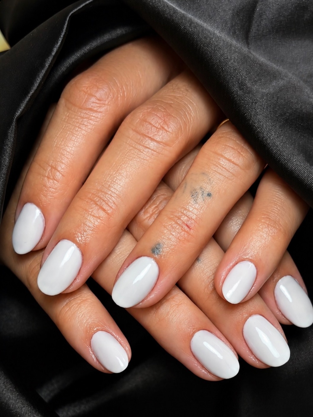 Witte gelnagels, glanzend afgewerkt, op zwart satijn