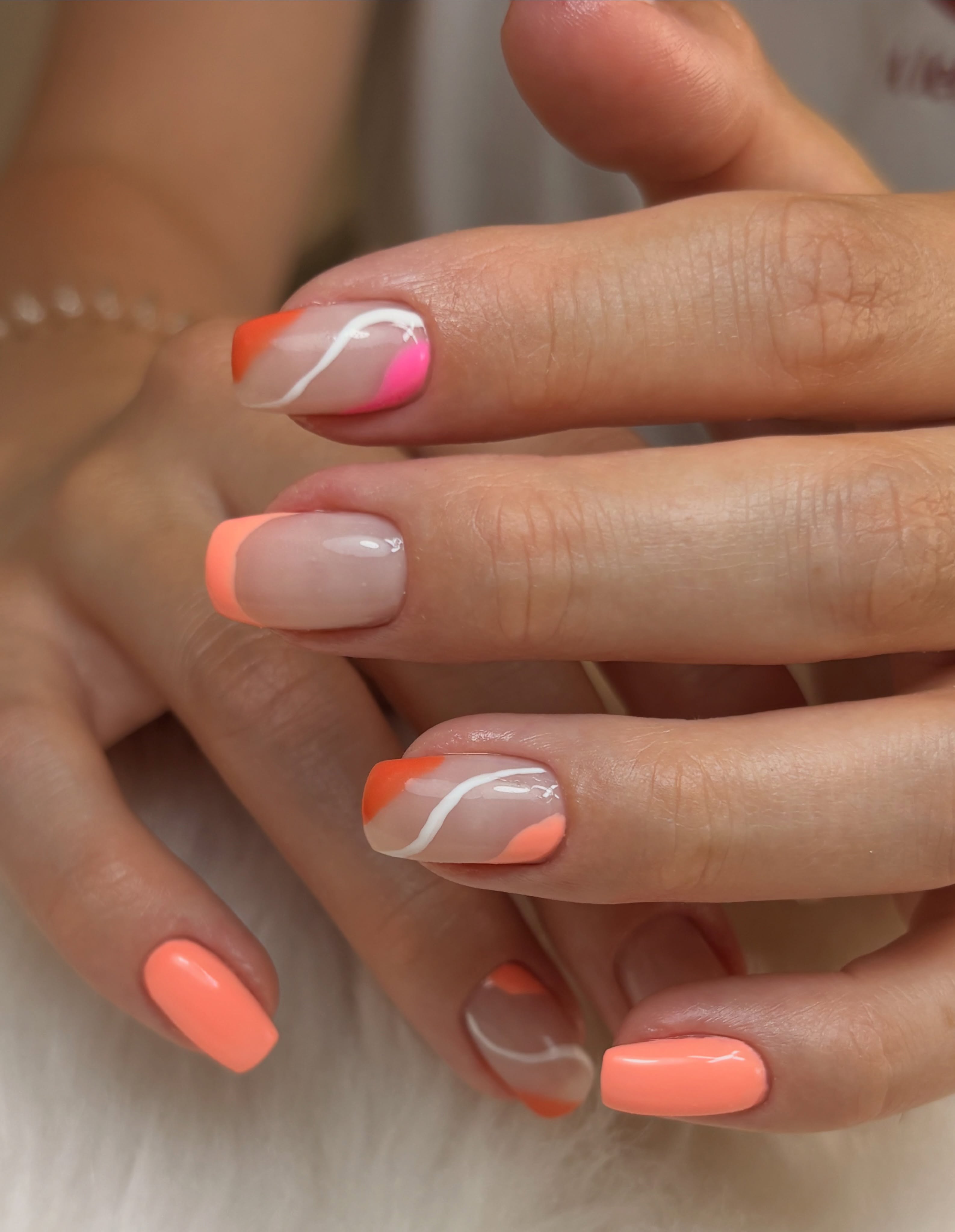 Perzikkleurige nail art met witte lijnen en een neonroze accent