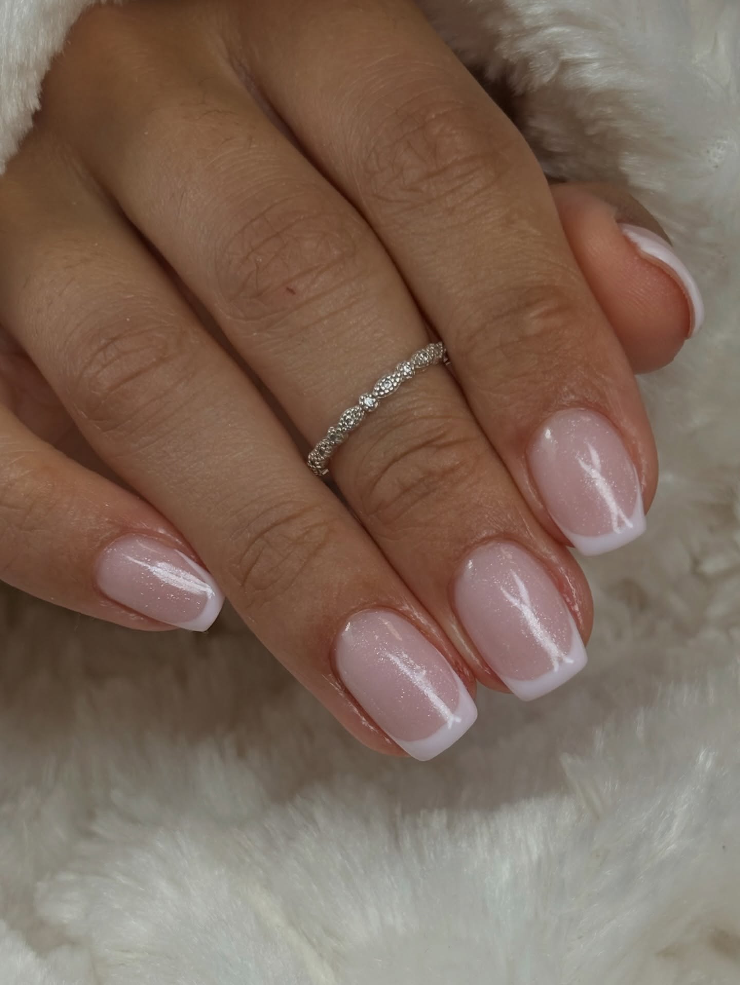 French nagels met glitter op wit bont, met een zilveren ring